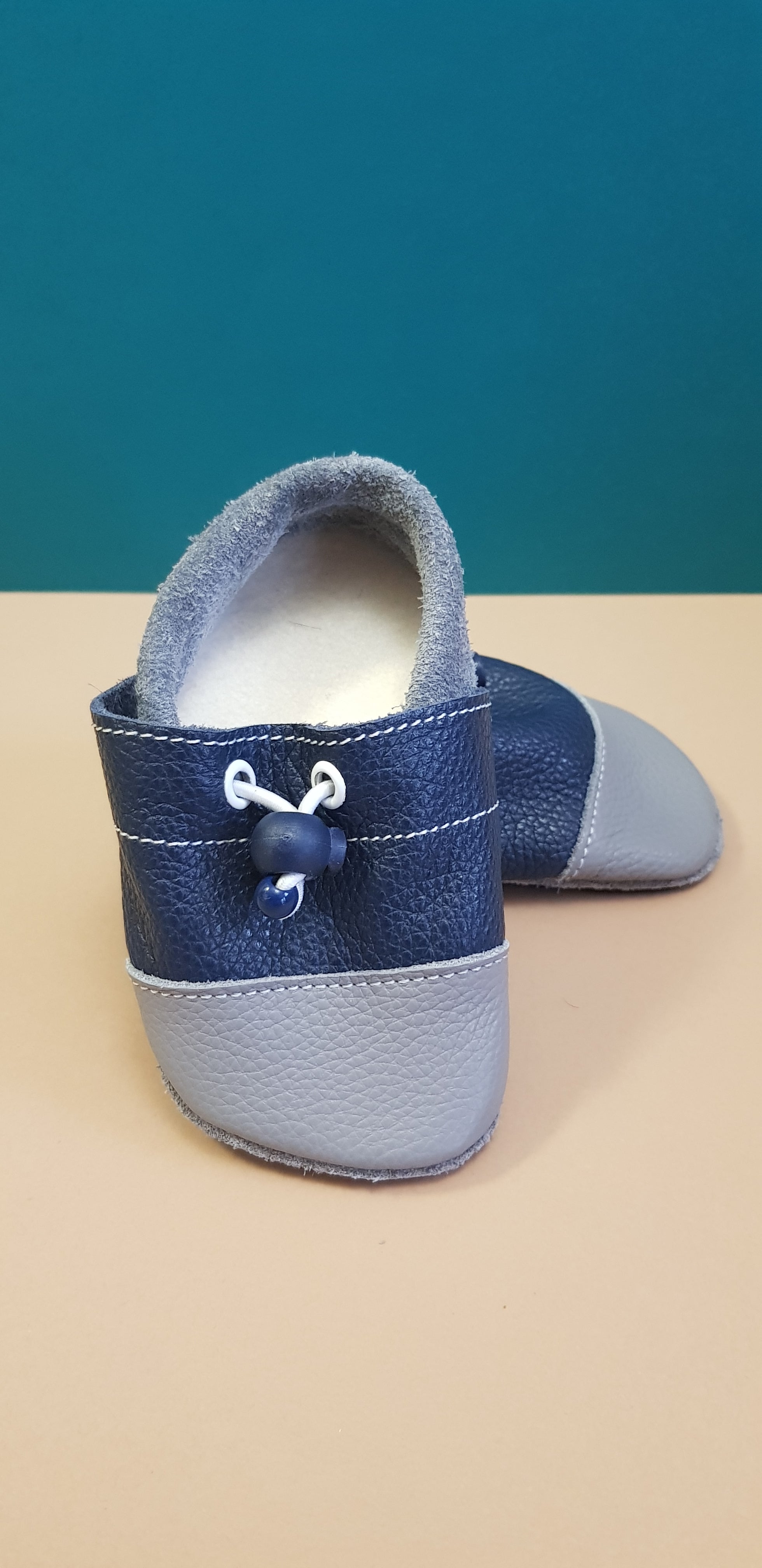 Navy and Grey Nohatka soft sole booties/slippers for babies and toddler, anatomically shaped from soft leather with adjustable ankle fastening and anti slip indoor/outdoor sole